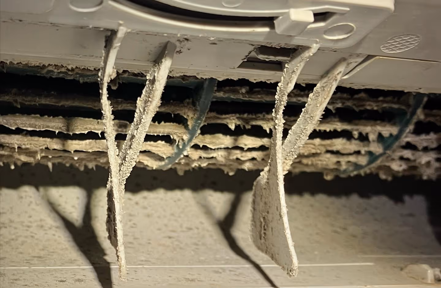 Close-up of heavily dust-covered air conditioner vents with clogged fins.