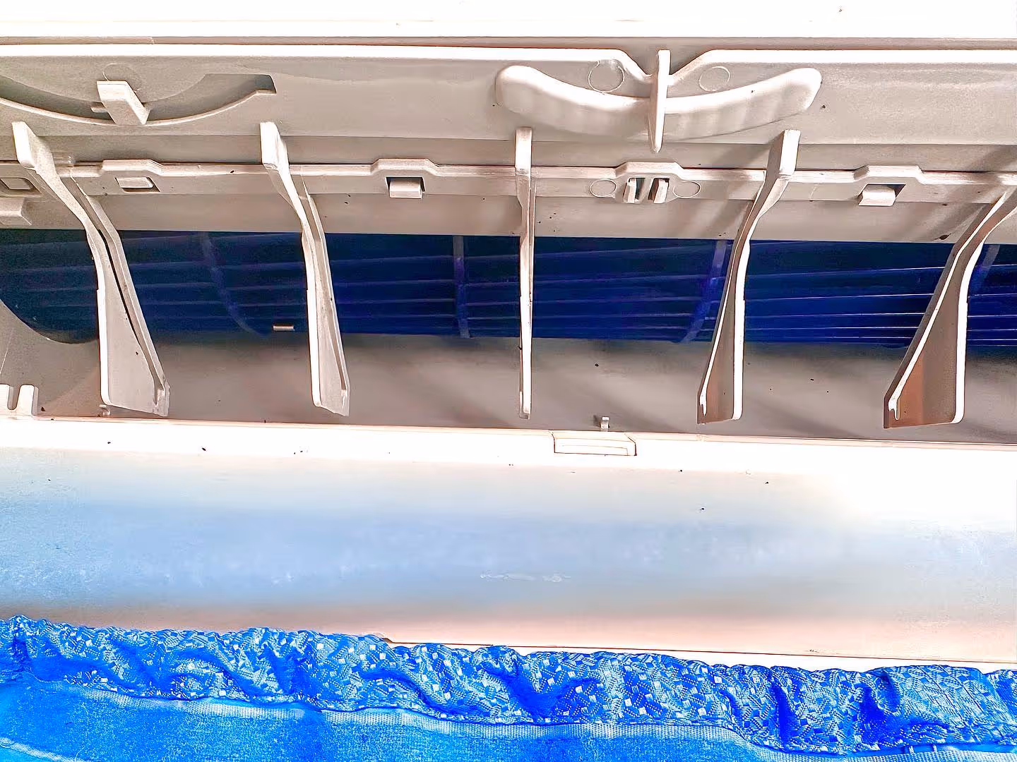 Close-up of air conditioner vents with blue fabric beneath.